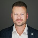 Professional headshot of man in blazer and white shirt