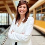 Smiling woman in white blazer indoors