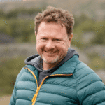 Smiling man in green puffer jacket outdoors