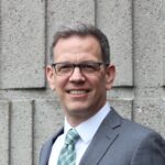 Smiling man in suit and glasses outdoors