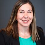 Smiling woman in blazer against gray background