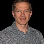 Man in patterned shirt against black background