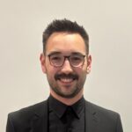 Smiling man with glasses in black suit