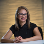 Professional woman with glasses smiling at desk