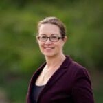 Smiling woman with glasses in outdoor setting