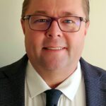 Man wearing glasses in suit and tie headshot