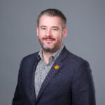 Professional headshot of smiling man in blazer