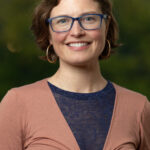 Smiling woman with glasses and hoop earrings outdoors