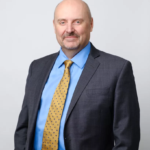 Bald man in suit and yellow tie headshot