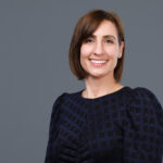 Smiling woman with short brown hair, gray background
