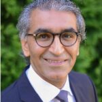 Smiling man in suit with glasses outdoors