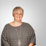 Smiling woman with short blonde hair, patterned top