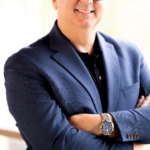 Smiling bald man in blue blazer and glasses