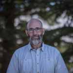Bald man with glasses and gray beard outdoors