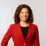 Smiling woman in red blazer studio portrait