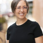 Smiling woman with short gray hair and red glasses