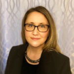 Professional headshot of woman wearing glasses and blazer