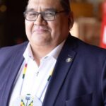 Man in suit wearing beaded medallion necklace