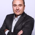 Smiling man in dark blazer with crossed arms
