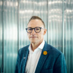 Man in glasses wearing teal blazer indoors