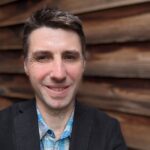 Smiling man in blazer against wooden wall