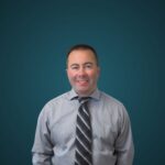 Smiling man in dress shirt and tie, teal background