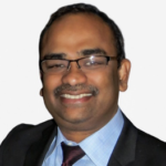 Smiling man wearing glasses, suit, and tie