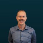 Smiling man with mustache in gray shirt