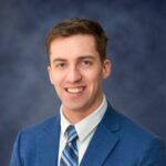 Professional headshot of smiling man in blue suit
